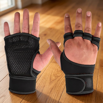 Pair of black weightlifting gloves worn on both hands, palm-up view on a hardwood floor showing the honeycomb grip pad and wrist wraps.